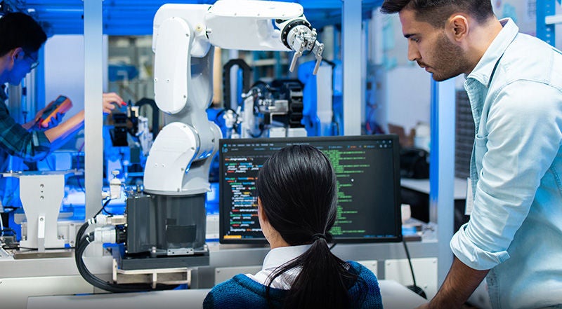 Fachkräfte arbeiten an einem Robotersystem und überprüfen dessen Steuerung.