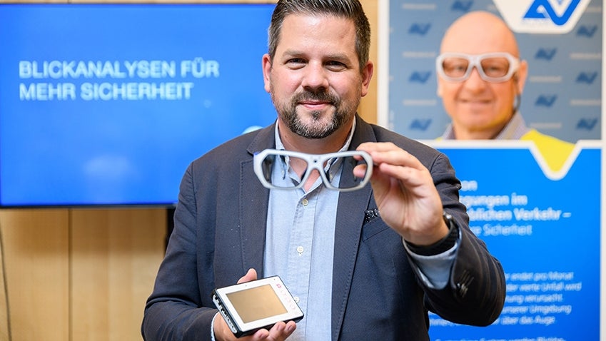 Bild zeigt einen Mann, der eine Eyetracking-Brille in der Hand hält