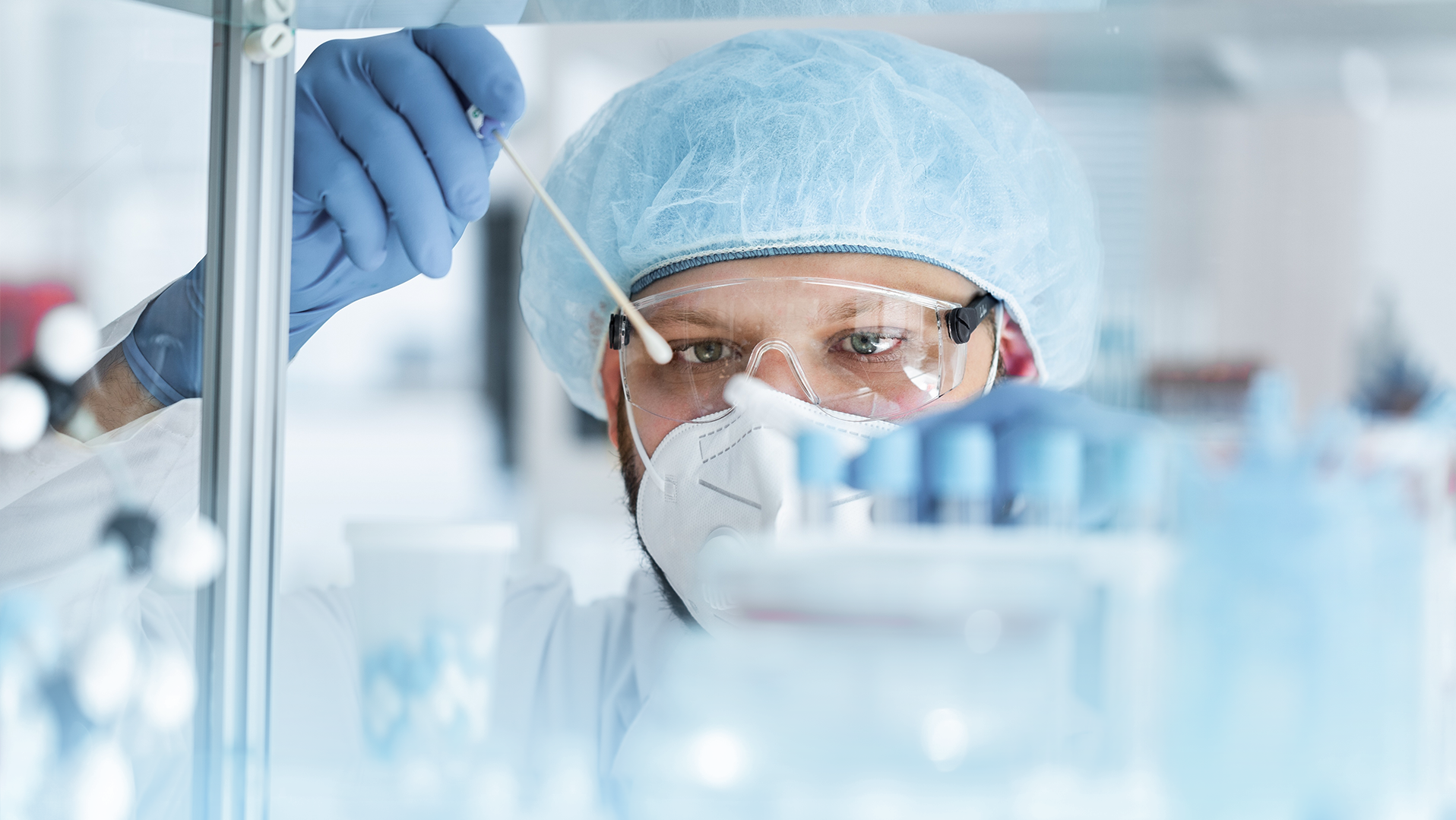 Ein Mann in Schutzkleidung und Schutzbrille nimmt eine Probe
