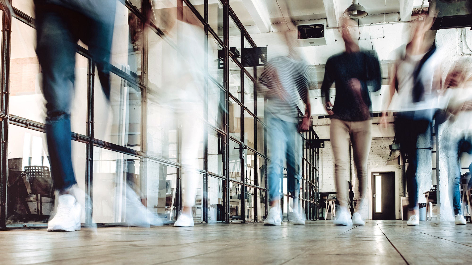 Young people work in modern office mehrere Personen gehen durch eine Büroumgebung, man sieht die Menschen aber nur schemenhaft