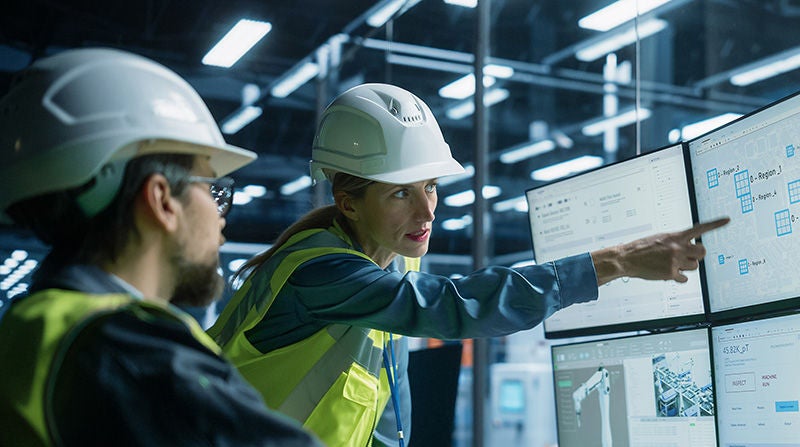 Personen in Schutzkleidung planen Produktionsabläufe an mehreren Monitoren.