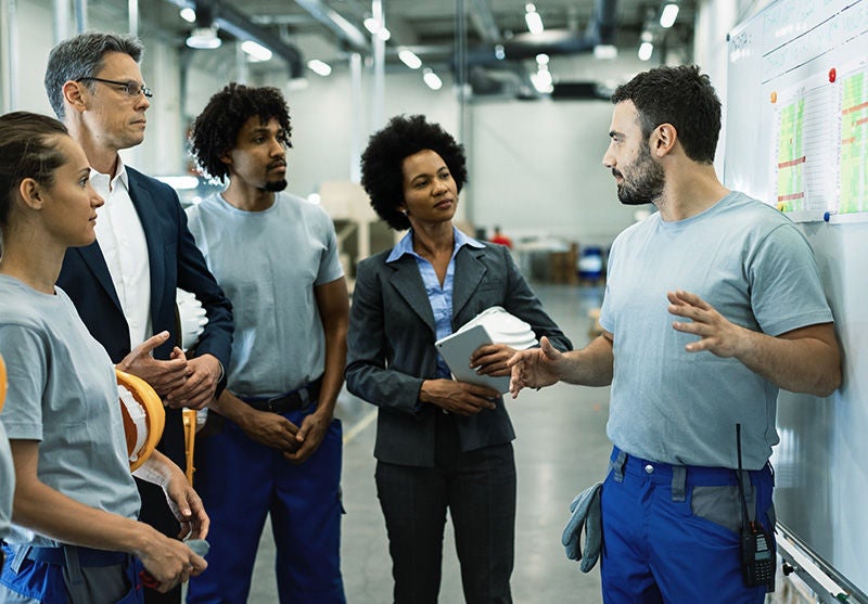 Young worker giving presentation in front of whiteboard in a factory. , Young worker giving presentation in front of whiteboard in a fac