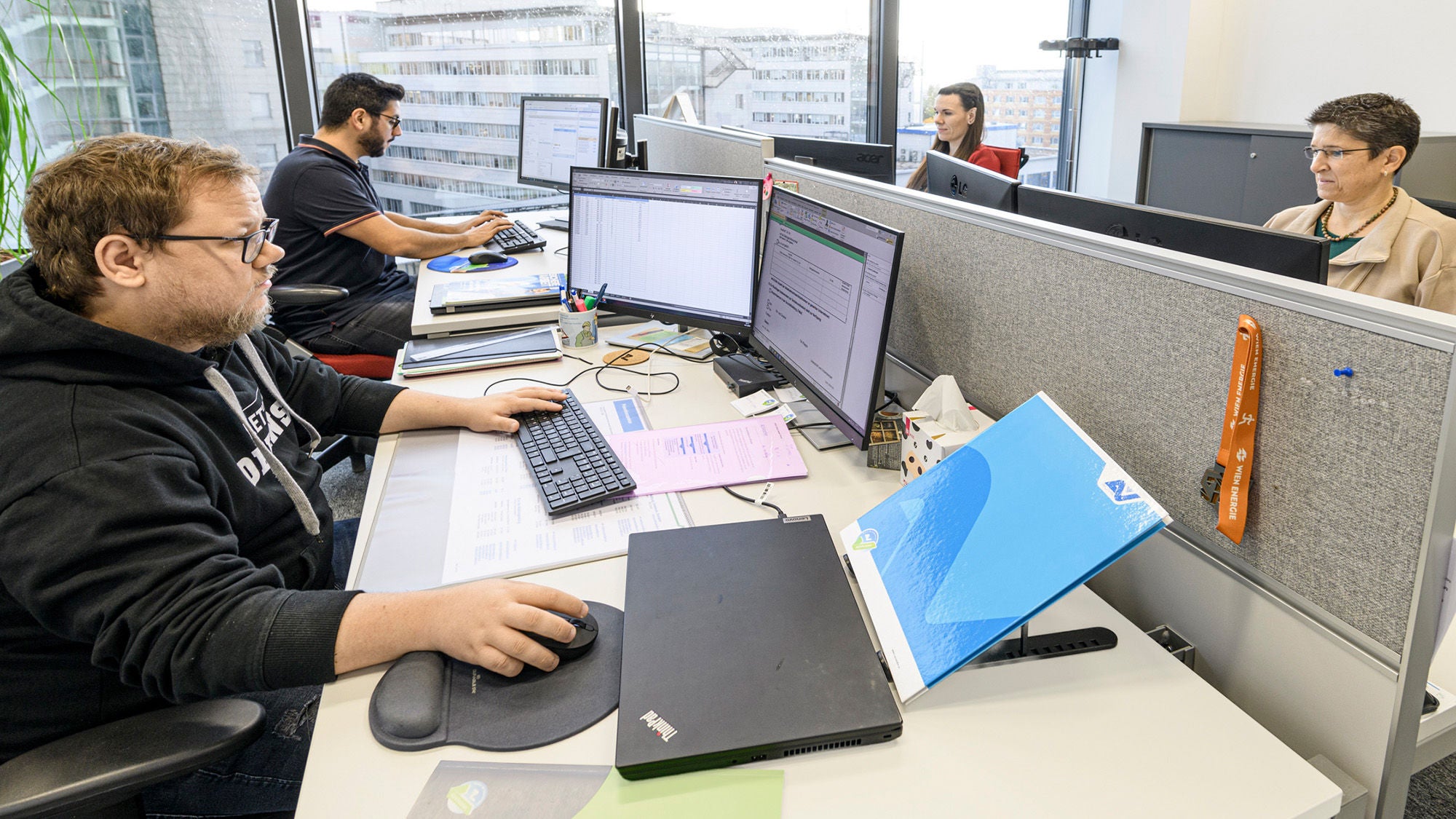 ein Büro mit Personen, die vor ihren Computern sitzen und arbeiten