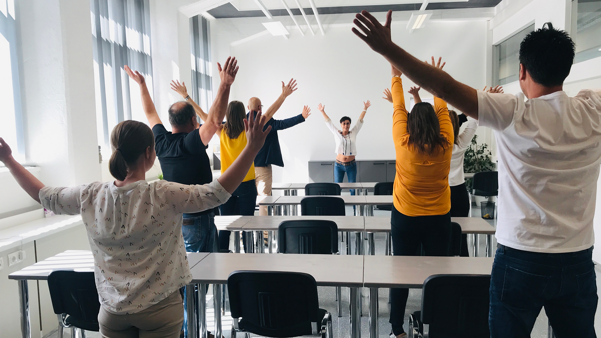 In einem Vortragssaal machen die Beschäftigten Turnübungen zur Entspannung