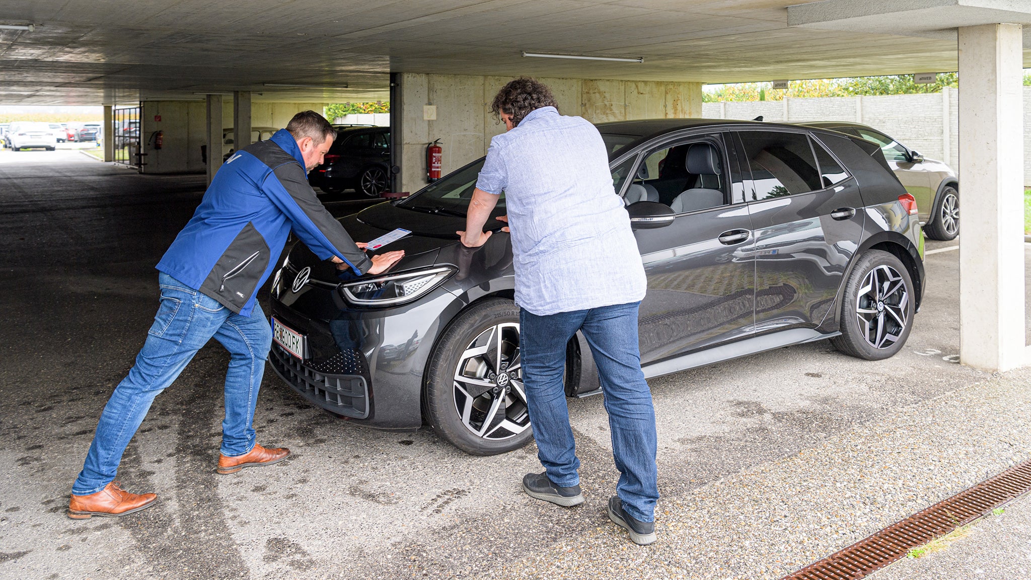 zwei Männer praktizieren Dehnübungen am Auto gelehnt
