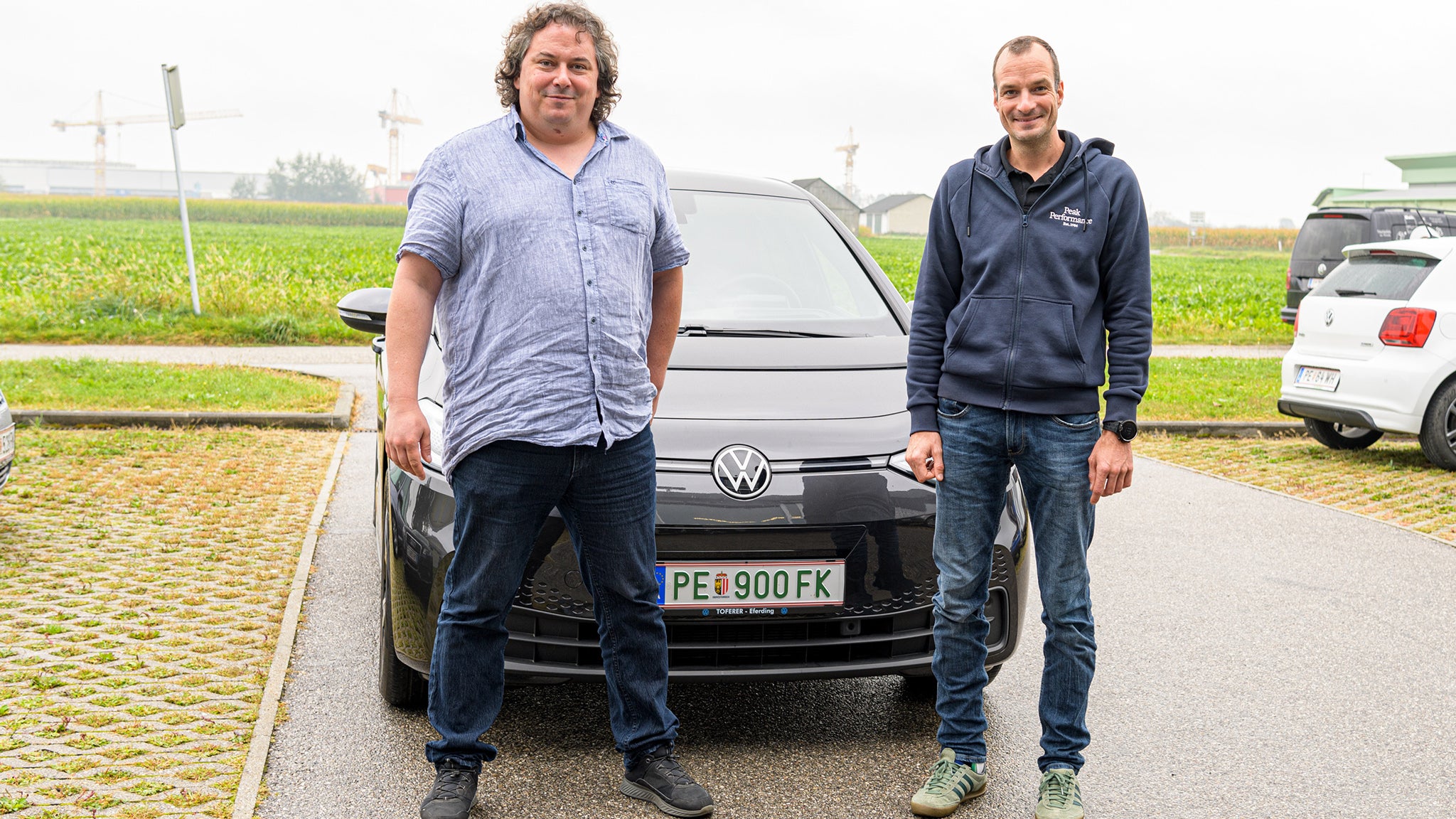 Zwei Männer stehen lächelnd vor einem Auto