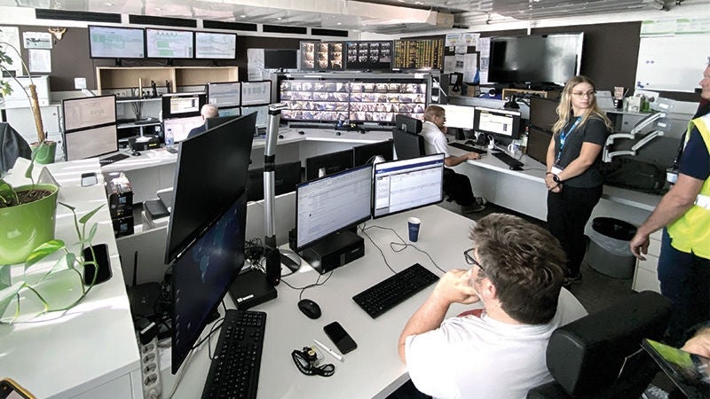 Ein großer Büroraum mit zahlreichen Schreibtischen, Monitoren und einigen Personen, die auf die Monitore blicken