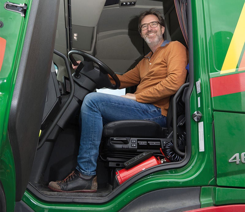 ein Mann sitzt in einem LKW und lächelt bei geöffneter Türe heraus