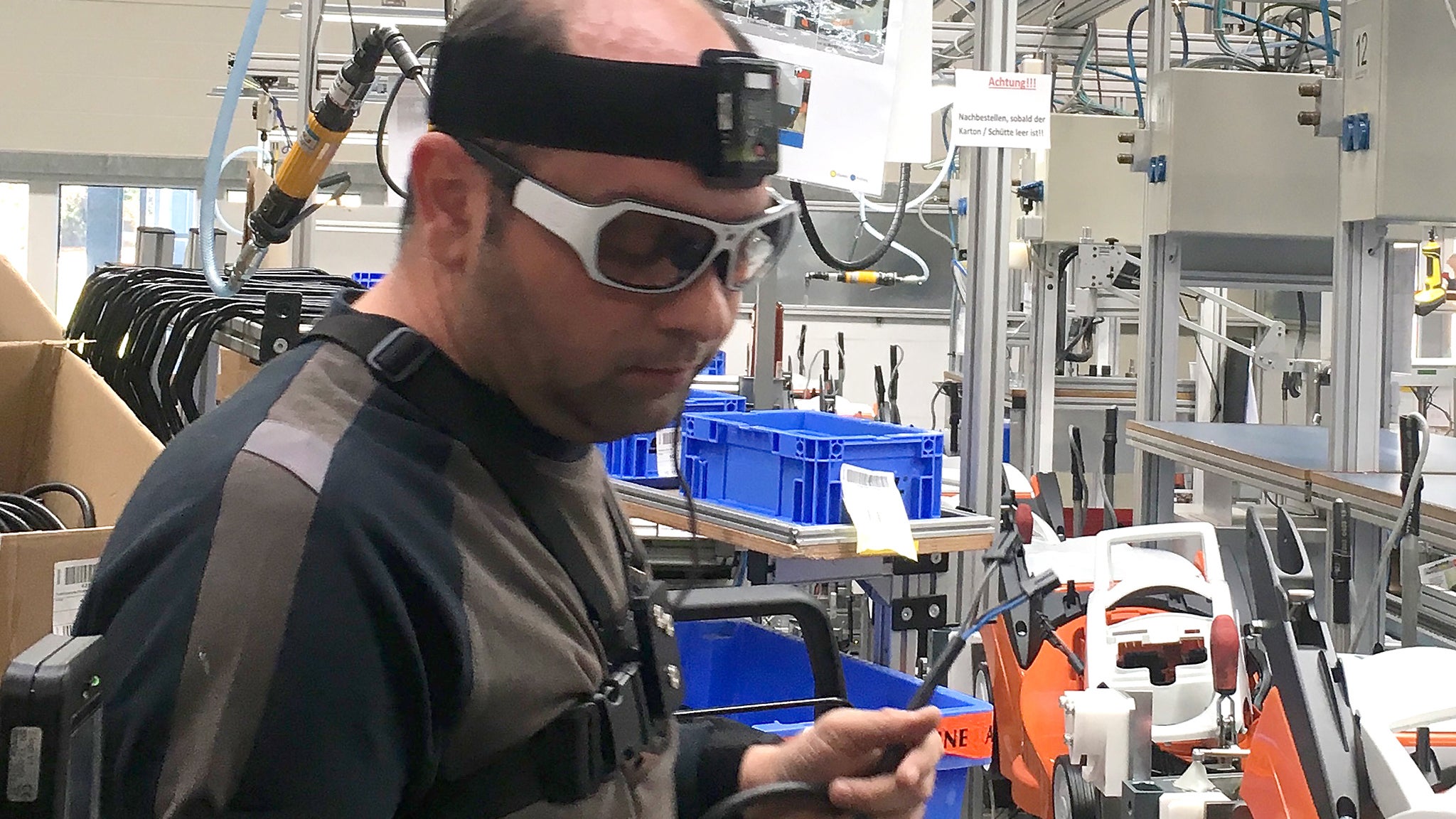 Das Bild zeigt einen Mann an einer Produktionsstraße für Gartengeräte. Dieser Mann trägt eine Eyetracking-Brille