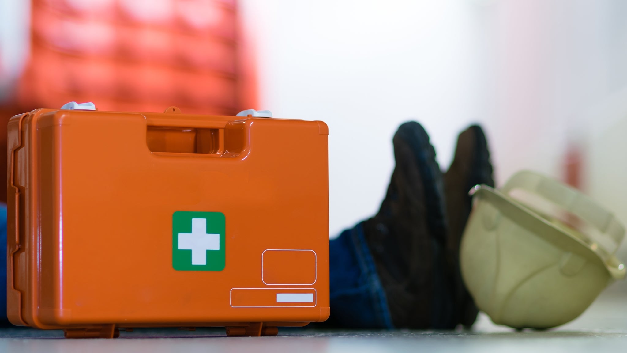 Mann liegt wegen Arbeitsunfall am Boden ein Erste Hilfe Set steht neben ihm