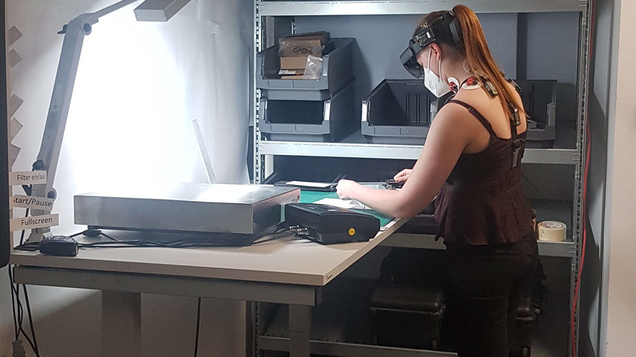 Eine junge Frau führt an einer Werkbank eine Tätigkeit aus