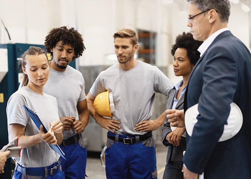 Female worker showing production reports to company managers in a factory. , Female worker showing production reports to company managers in