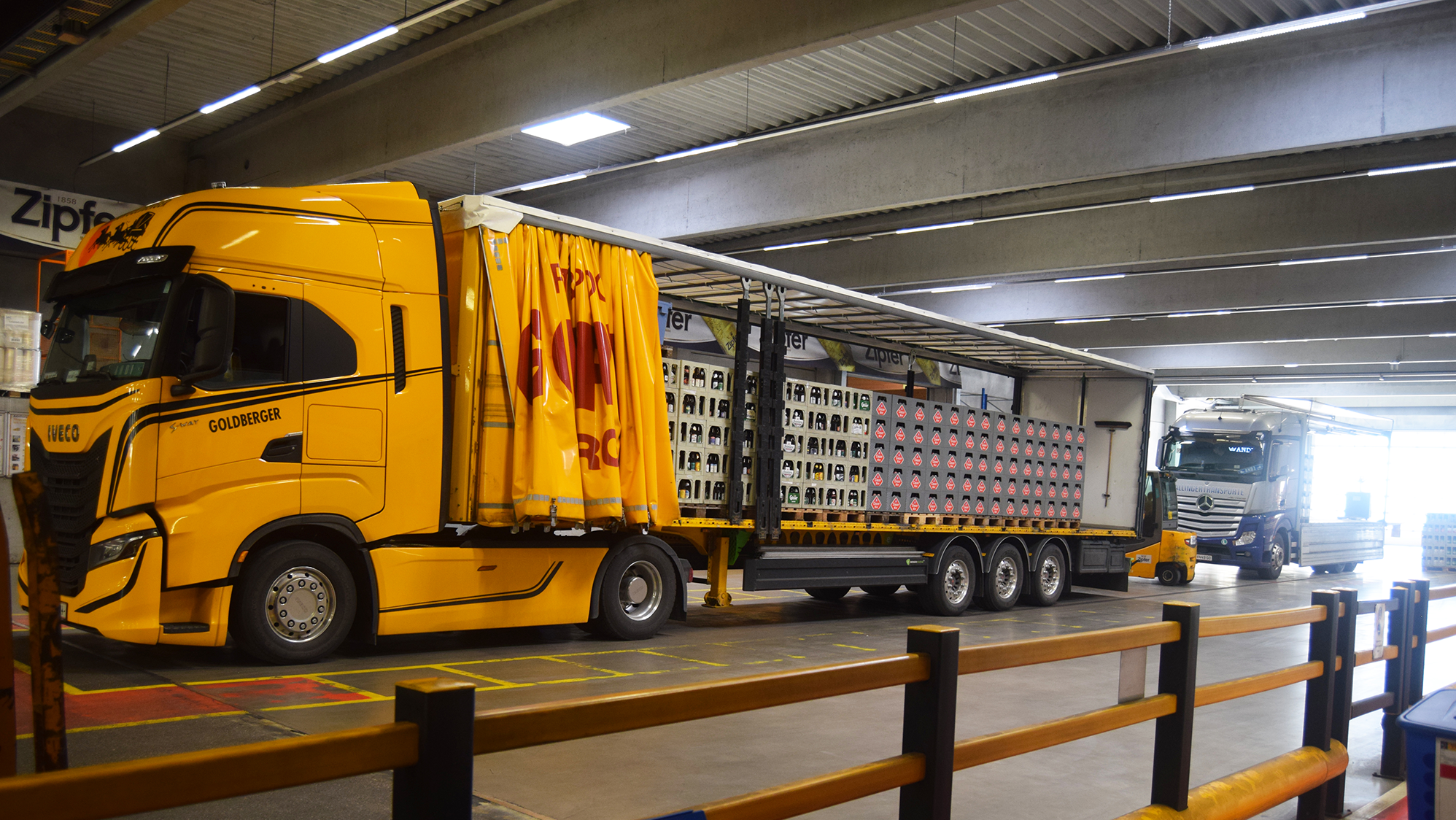 ein mit Bierkisten beladener LKW steht in einer Halle, dahinter sieht man einen weiteren LKW