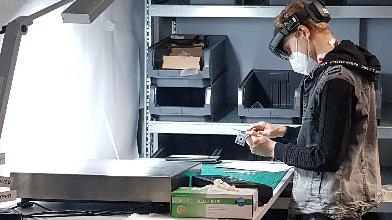 Eine junger Mann führt an einer Werkbank eine Tätigkeit aus