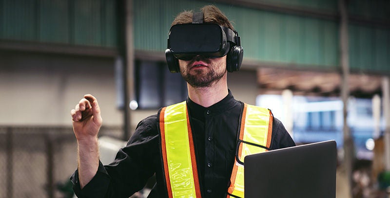 Person mit VR-Brille erkundet virtuell einen Arbeitsbereich.