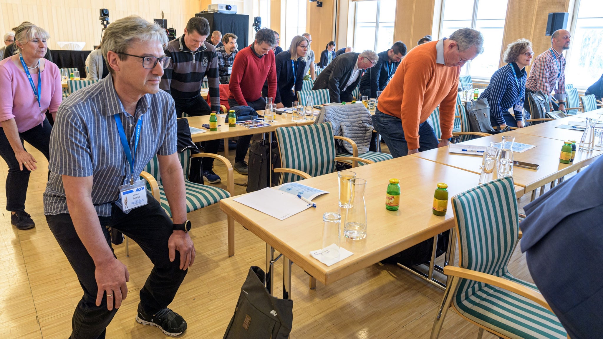 Teilnehmer:innen an einem Workshop praktizieren leichte Gymnastik neben dem Schreibtischen