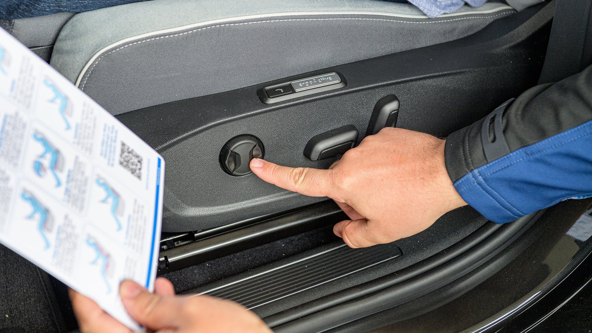 In der Autotür angebrachter Knopf, Finger zeigt darauf, die andere Hand zeigt eine Schautafel zur richtigen Ausrichtung