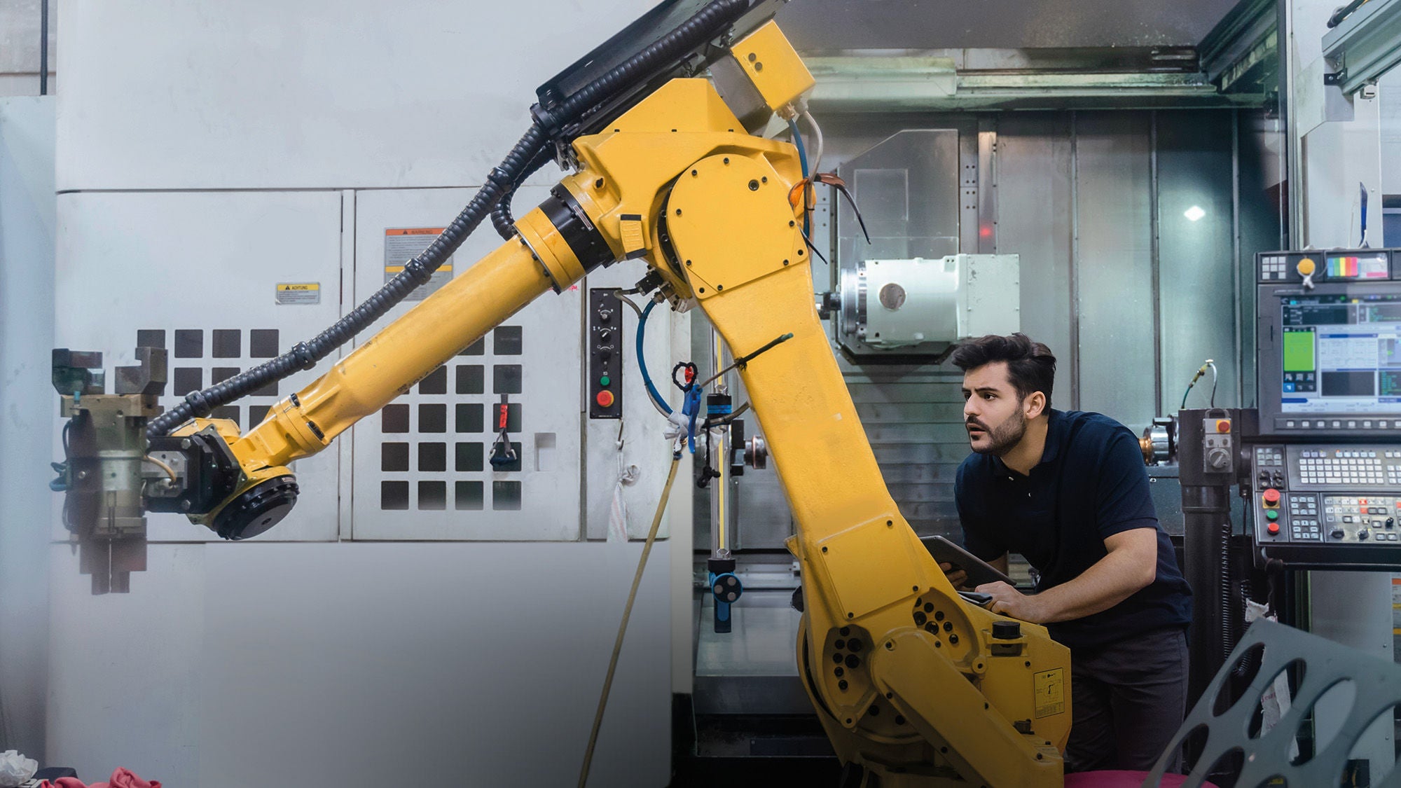 ein Mann steuert einen Roboterarm, der ein Stück Stoff anhebt