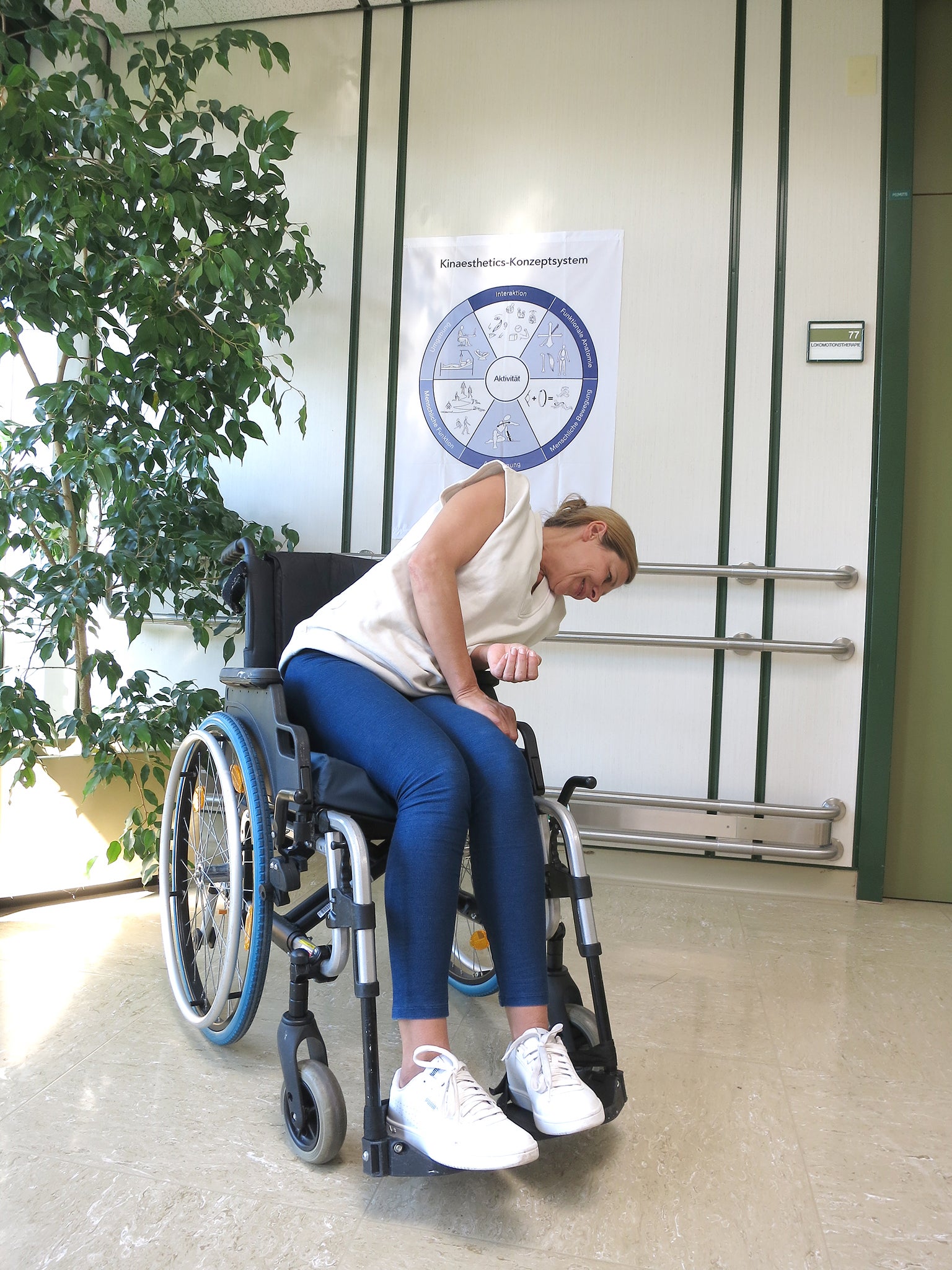 Frau in Rollstuhl beugt sich seitlich